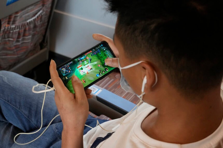 Un hombre juega a un juego online de la plataforma de juegos china Tencent en un tren de Henan a Pek