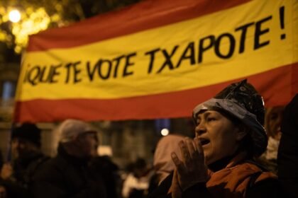Una manifestante con la bandera de España y el texto "Que te vote Txapote", durante una protesta en la calle Ferraz