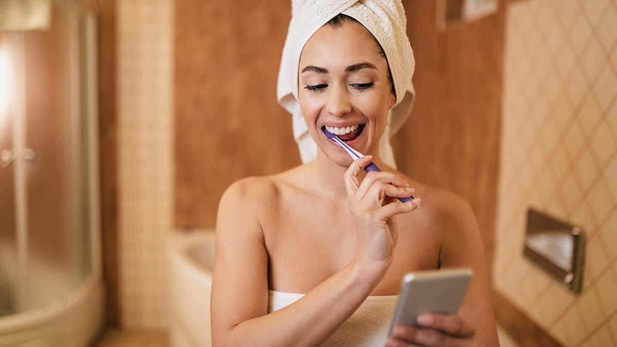 Mujer monitorea la duración del cepillado con el cronómetro del celular