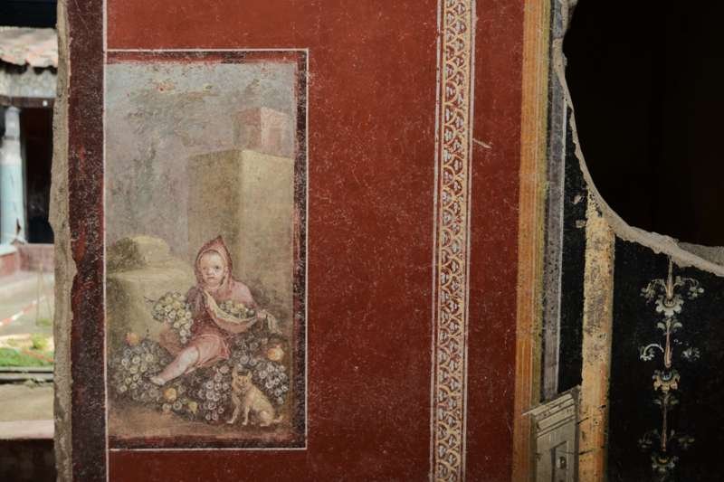 Pintura que representa a un niño junto a un perrito, en la casa de los Pintores Trabajando, en Pompeya.