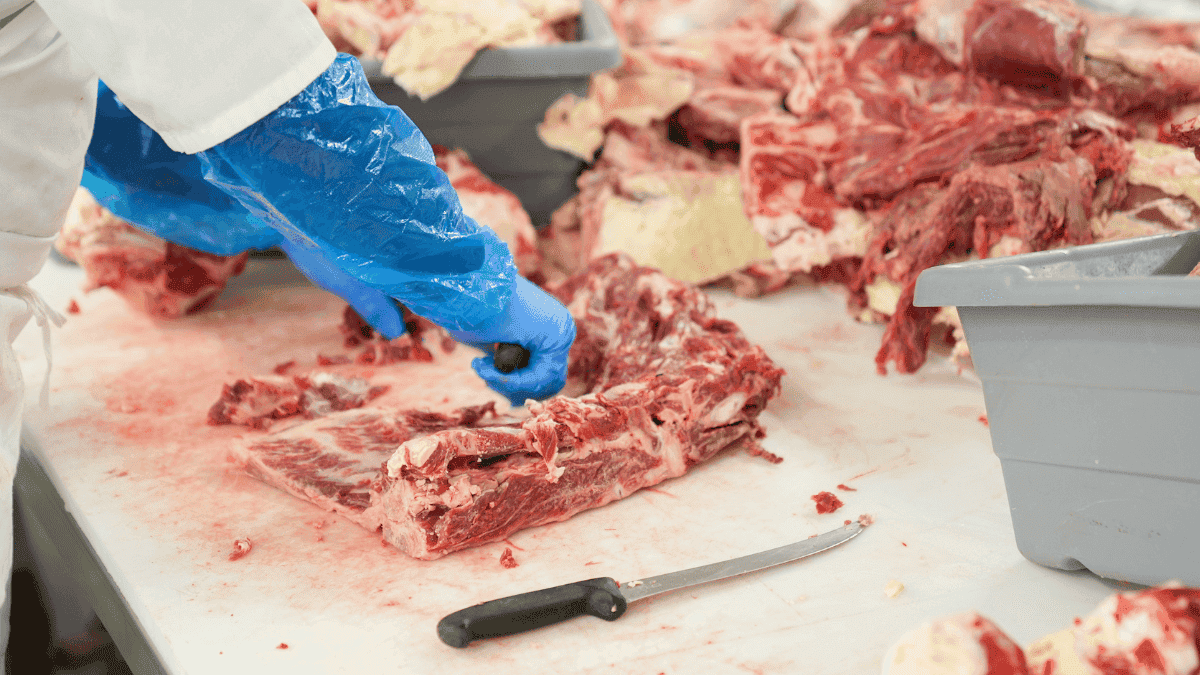 Carnicero manipulando trozos de carne cruda.